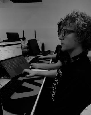 Equipe técnica colaborando enquanto escreve códigos, com computadores, notebooks e telas exibindo linhas de programação em um ambiente de trabalho.